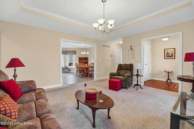 carpeted living room featuring a raised ceiling, crown molding, and a chandelier