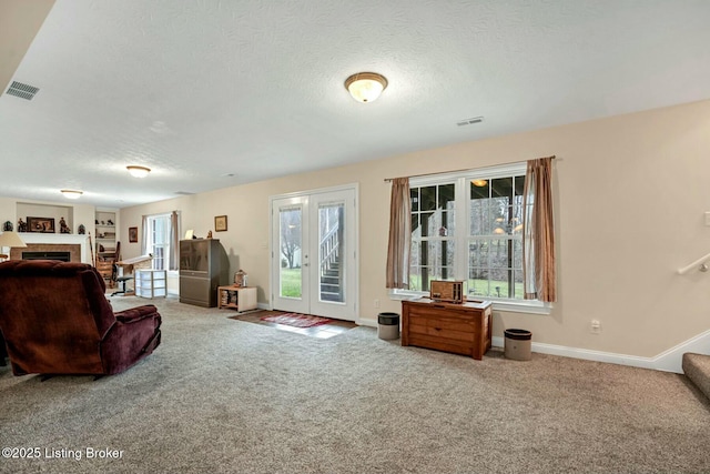 carpeted living room with a textured ceiling, a fireplace, and french doors