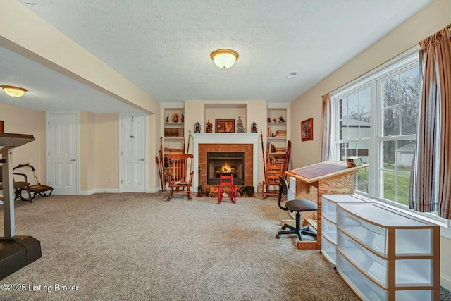 carpeted office featuring a tiled fireplace, built in features, and a textured ceiling