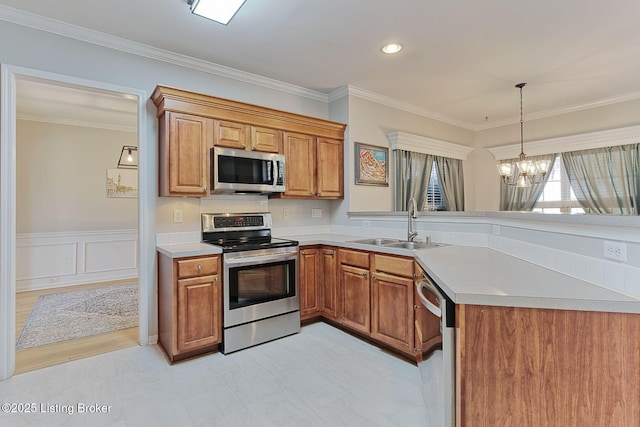 kitchen featuring sink, crown molding, a chandelier, hanging light fixtures, and appliances with stainless steel finishes