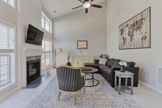 living room featuring high vaulted ceiling, a premium fireplace, and ceiling fan