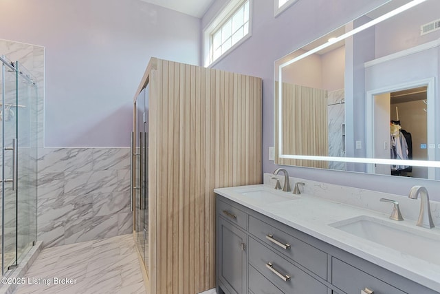 bathroom with a shower with door, vanity, and tile walls