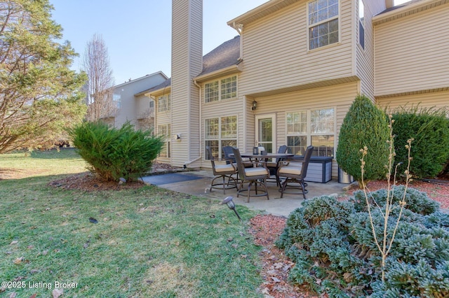 back of property featuring a hot tub, a patio, and a lawn