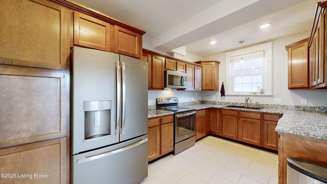 kitchen featuring sink, light stone countertops, hanging light fixtures, and appliances with stainless steel finishes