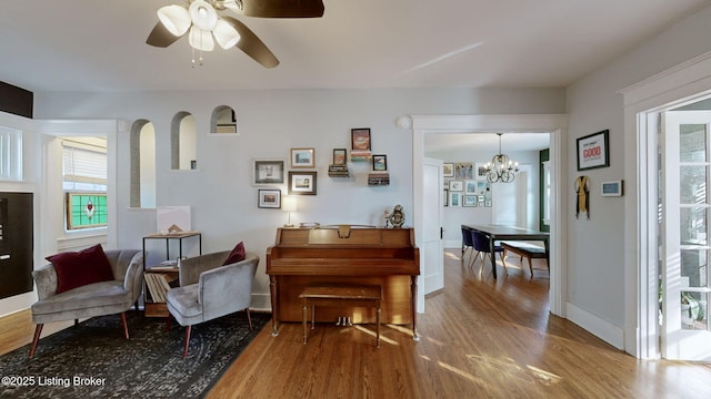 sitting room featuring hardwood / wood-style floors and ceiling fan with notable chandelier