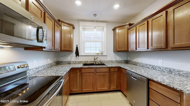 kitchen featuring light tile patterned flooring, decorative light fixtures, sink, stainless steel appliances, and light stone countertops