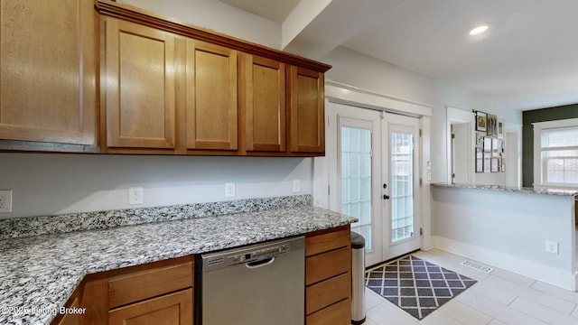 kitchen featuring light stone countertops, stainless steel dishwasher, and french doors