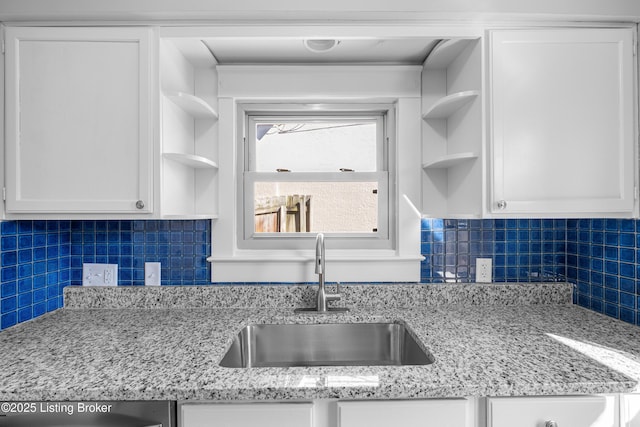 kitchen featuring light stone countertops, sink, white cabinets, and decorative backsplash