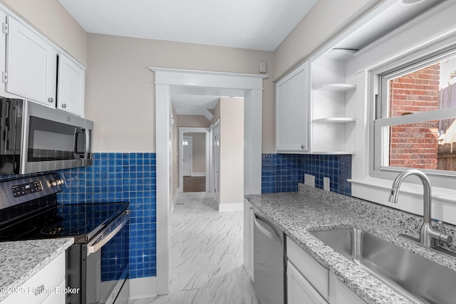 kitchen featuring appliances with stainless steel finishes, sink, white cabinets, and light stone counters