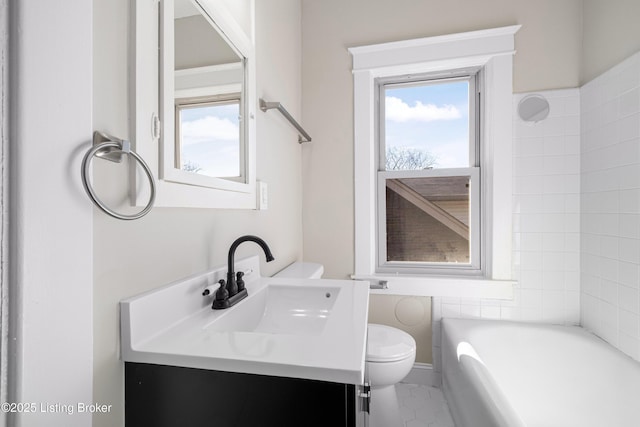 bathroom featuring vanity, plenty of natural light, a tub, and toilet