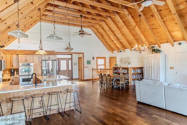 kitchen with stainless steel appliances, ceiling fan with notable chandelier, pendant lighting, and light brown cabinetry