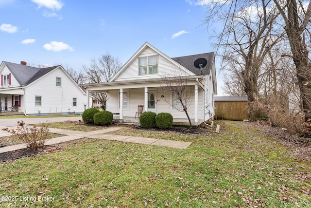 view of front of property with a storage shed, a front yard, and covered porch