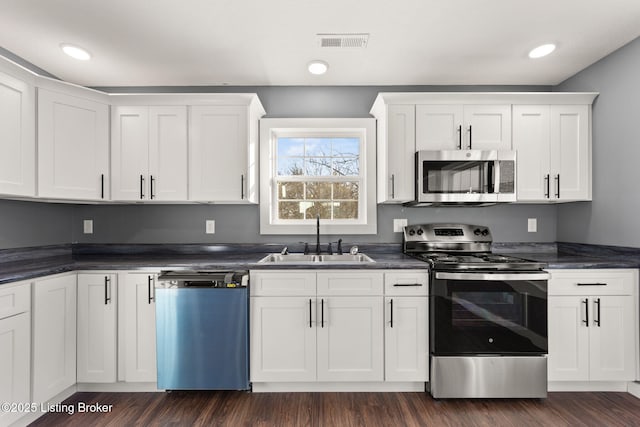 kitchen with dark wood-type flooring, appliances with stainless steel finishes, sink, and white cabinets