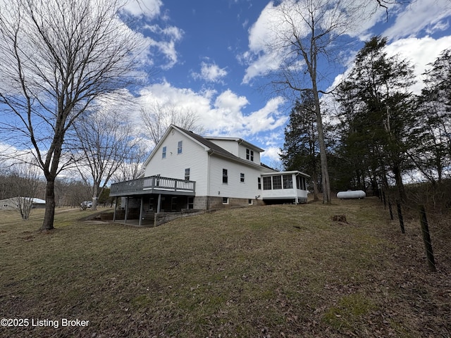 rear view of house featuring a yard, a sunroom, and a deck