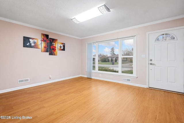 entryway with ornamental molding, a textured ceiling, and light wood-type flooring