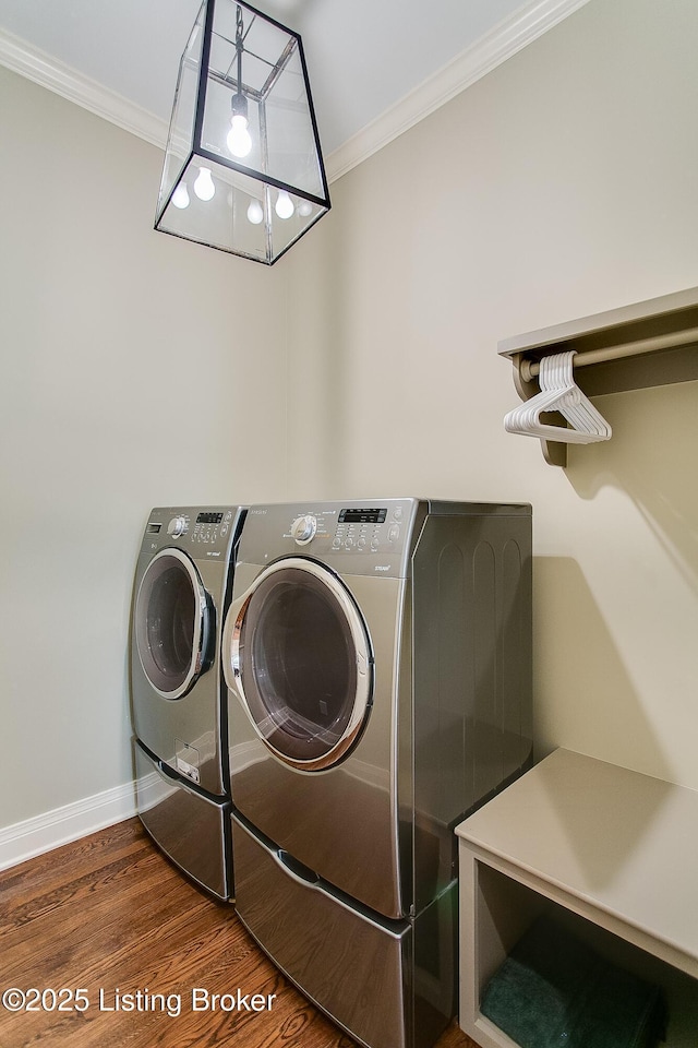 laundry room featuring crown molding, washer and dryer, and dark wood-type flooring