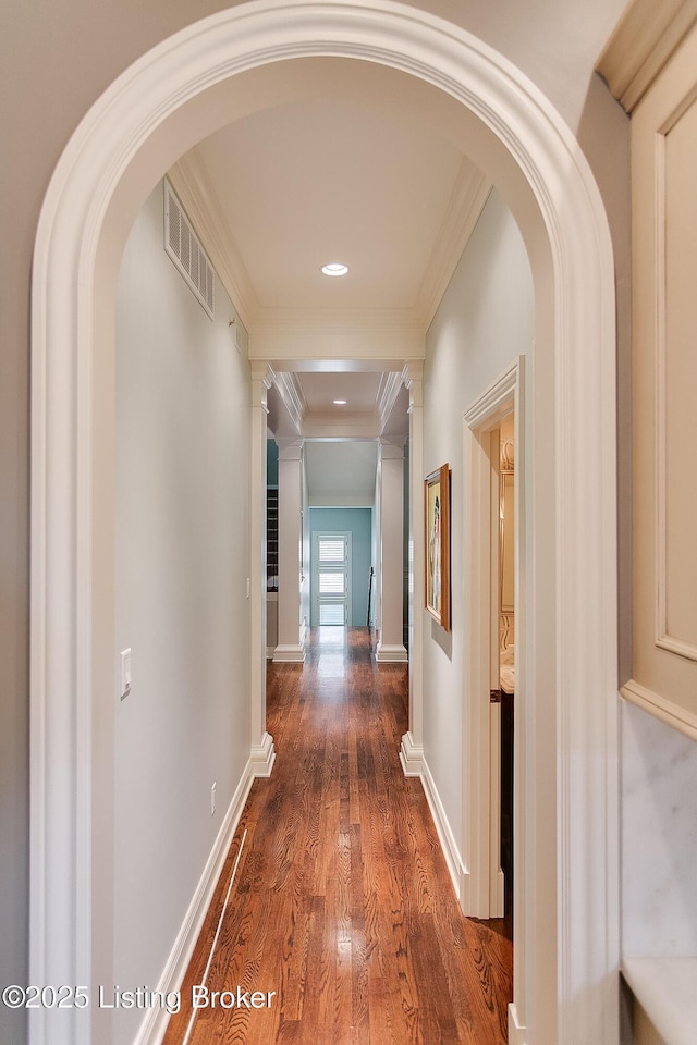 hall featuring decorative columns, crown molding, and dark hardwood / wood-style flooring