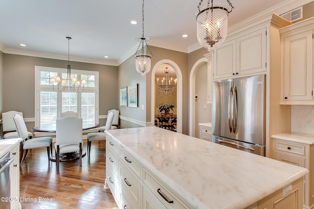 kitchen with pendant lighting, a notable chandelier, stainless steel refrigerator, and a kitchen island