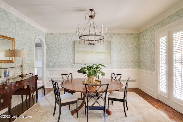 dining room featuring hardwood / wood-style floors, crown molding, a wealth of natural light, and a notable chandelier