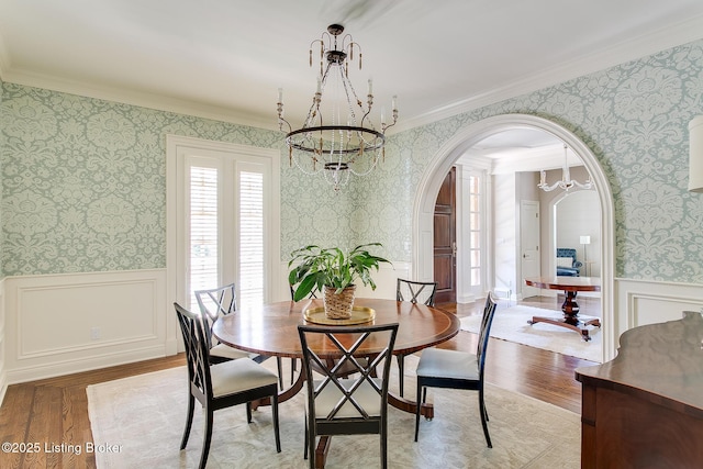 dining room with ornamental molding, light hardwood / wood-style floors, and a notable chandelier