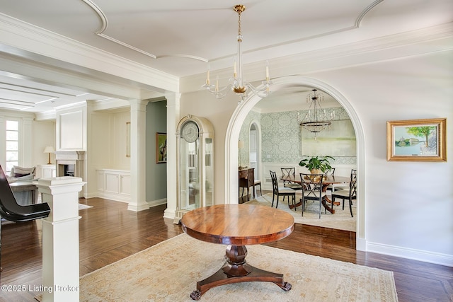 interior space with ornate columns, crown molding, dark wood-type flooring, and a chandelier