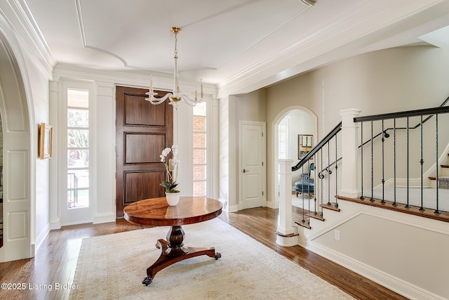 foyer with crown molding, a chandelier, and hardwood / wood-style flooring