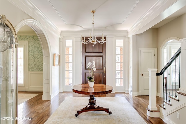 entrance foyer featuring wood-type flooring, a notable chandelier, and crown molding