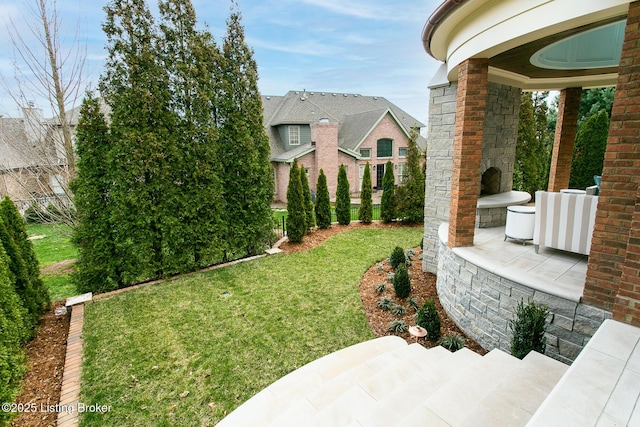 view of yard featuring an outdoor fireplace and a patio