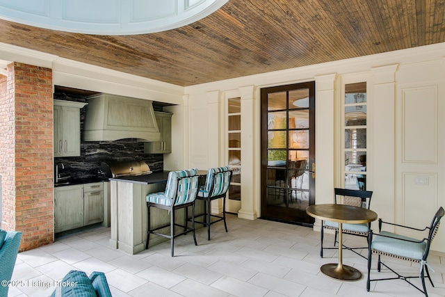 kitchen featuring premium range hood, a breakfast bar, tasteful backsplash, light tile patterned floors, and wooden ceiling