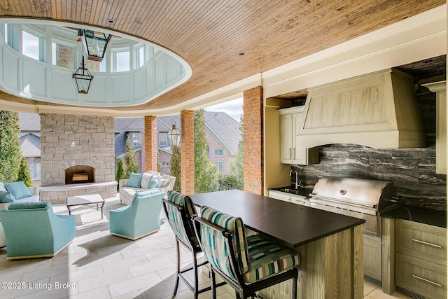 view of patio featuring a bar, a grill, an outdoor living space with a fireplace, and an outdoor kitchen