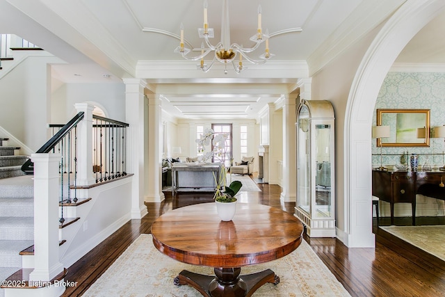 foyer entrance featuring decorative columns, dark hardwood / wood-style floors, and a chandelier