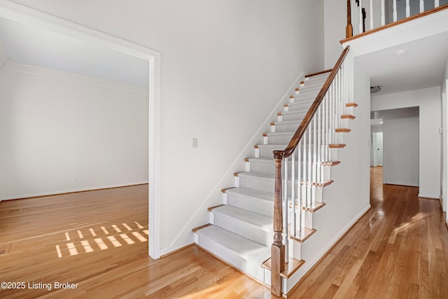 stairs featuring crown molding and hardwood / wood-style floors