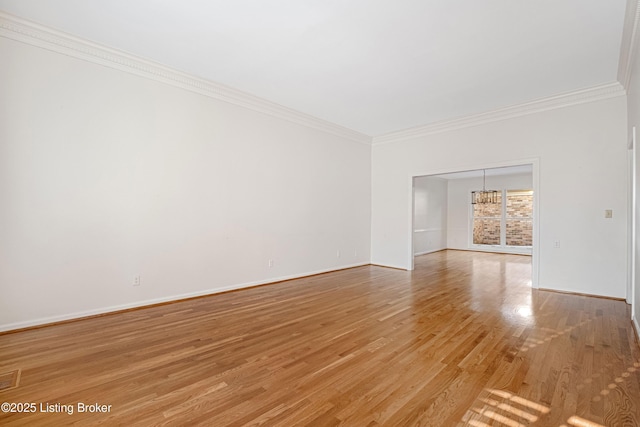 unfurnished room featuring hardwood / wood-style flooring, ornamental molding, and a notable chandelier