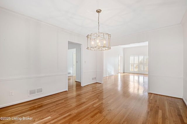 empty room with wood-type flooring, ornamental molding, and an inviting chandelier