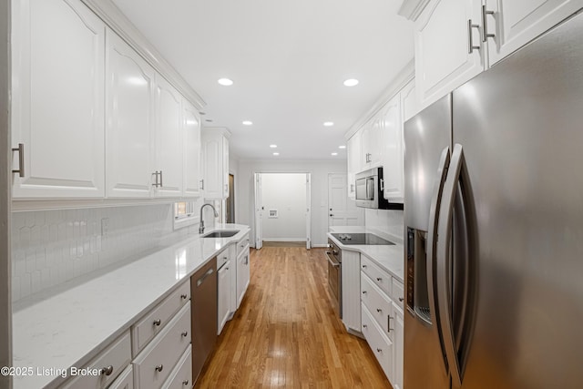 kitchen with light stone countertops, appliances with stainless steel finishes, sink, and white cabinets