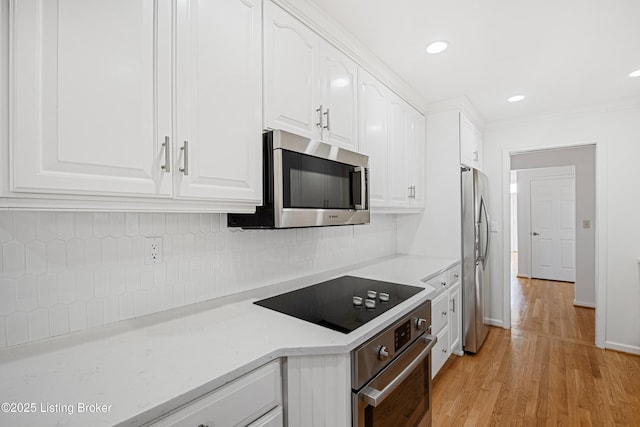 kitchen with crown molding, appliances with stainless steel finishes, white cabinetry, decorative backsplash, and light wood-type flooring