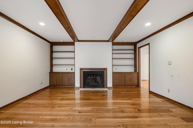 unfurnished living room featuring hardwood / wood-style floors, beam ceiling, built in features, and ornamental molding