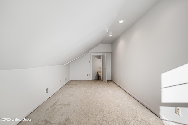 bonus room with vaulted ceiling and light colored carpet