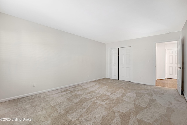 unfurnished bedroom with light colored carpet and a closet