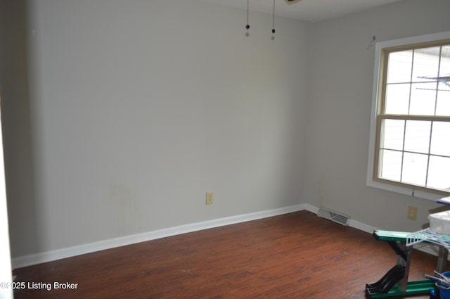 unfurnished room featuring a healthy amount of sunlight and dark wood-type flooring