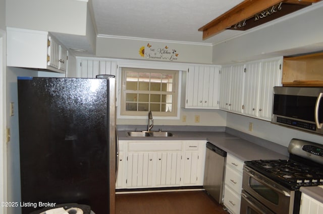 kitchen with sink, crown molding, appliances with stainless steel finishes, white cabinetry, and dark hardwood / wood-style floors