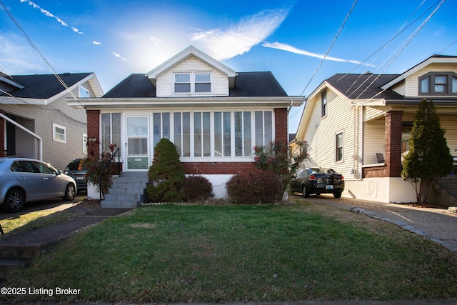 bungalow-style house featuring a sunroom and a front lawn