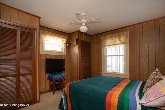 carpeted bedroom featuring ornamental molding, ceiling fan, and wood walls