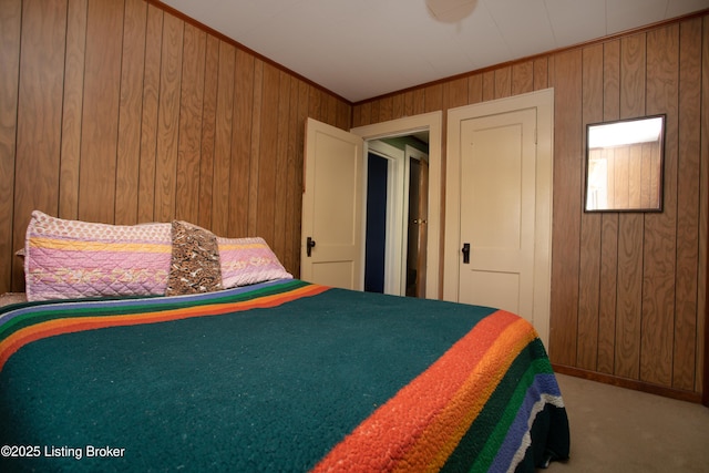 carpeted bedroom featuring ornamental molding and wooden walls