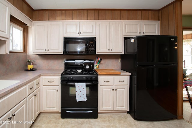 kitchen featuring ornamental molding, wooden walls, and black appliances