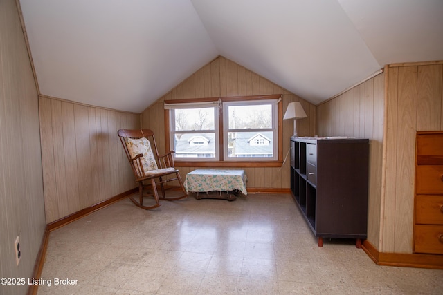 unfurnished room featuring vaulted ceiling and wooden walls