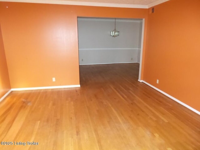 empty room featuring crown molding, baseboards, and wood finished floors