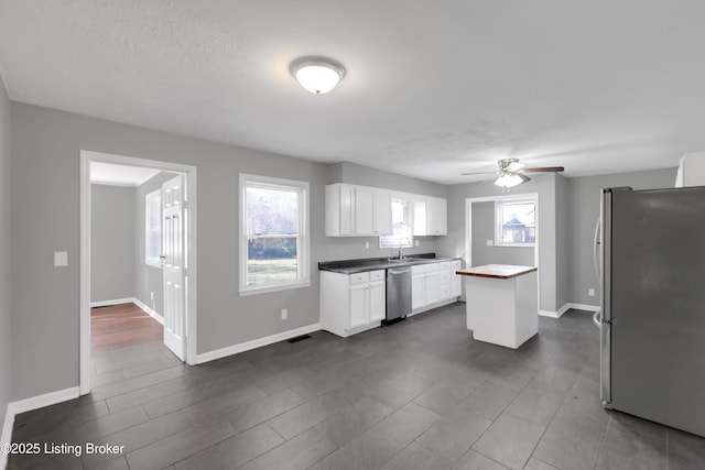 kitchen with sink, a textured ceiling, appliances with stainless steel finishes, ceiling fan, and white cabinets