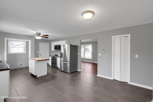 kitchen featuring wood counters, a center island, ceiling fan, stainless steel appliances, and white cabinets