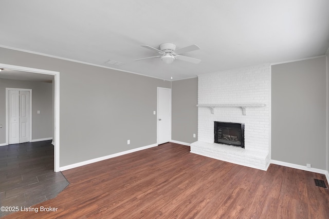 unfurnished living room featuring crown molding, dark hardwood / wood-style floors, a fireplace, and ceiling fan